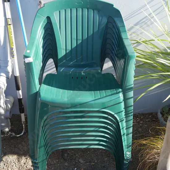 Stack of 9 green plastic chairs